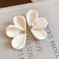 Macro detail of elegant cream resin flower earrings with gold textured pistil centers. - Beige