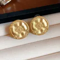 Close-up of matte gold stud earrings featuring a vintage floral embossed pattern - Round Printed Style (HE32188) / Gold