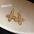 Gros plan détaillé de boucles d'oreilles fleurs plaquées or 18 carats avec zircons - Or