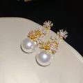 Close-up of elegant zircon flower earrings with large lustrous white pearls on a dish - Gold