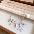 Detailed close-up of a beach-style necklace featuring starfish and shell charms with pearls - Choker Necklace / White