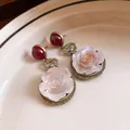 Detailed macro view of vintage resin rose earrings with elegant red bead accents - Antique Gold Round Rose Style / Red