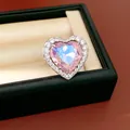 Close-up detail of a heart-shaped ring with iridescent pink stone and sparkling zircon halo - Heart Open Ring / Pink
