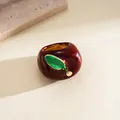 Detailed macro view of an elegant dark red apple ring with a vibrant green leaf detail - Red
