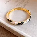 Close-up detail of a vintage bicolor enamel bangle with elegant gold finish and clasp - Gold-White-Black