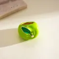 Close-up detail of vibrant green enamel apple-shaped ring with a gold-toned leaf - Green