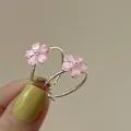 Primo piano di orecchini a cerchio con fiori rosa e perla centrale tenuti in mano - Rosa