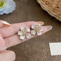 Close-up of French-style irregular camellia earrings with pearls and cubic zirconia - Stud Earrings / Gold and White