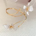 Vue détaillée d'un bracelet de bras doré avec d'élégantes fleurs en émail blanc - Bracelet de Bras Ouvert Fleur (HB5663) / Or-Beige
