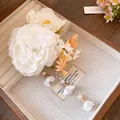 Close-up of elegant white fabric flower hair clip with dangling pearl tassels and petals - White