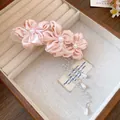 Close-up of elegant pink fabric flower hair clip with pearl tassel in a jewelry box. - Pink