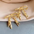 Close-up of elegant gold ribbon bow stud earrings with a smooth polished finish - Bow / Gold