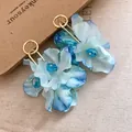 Macro detail view of blue fabric flower earrings with crystal accents and gold hoop - Blue