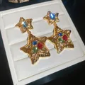 Gold hammered star earrings with multicolor crystals in luxury jewelry box display. - Pleated Star Style / Gold