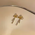 Vue détaillée de boucles d'oreilles nœud plaquées or avec zircons brillants - Clip d'Oreille Nœud à Franges / Une Paire / Or
