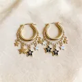 Close-up macro detail of gold hoop earrings with black enamel star charms and delicate chains - Enamel Star Tassel Style (HE32254) / Gold