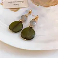 Detalle macro de resina verde oliva y cuentas jaspeadas en pendientes dorados. - Verde