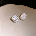Primo piano dei piccoli orecchini a dado in argento con frammenti di conchiglia e cristalli - Bianco