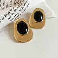 Detail shot of vintage gold-tone oval earrings featuring large black resin center pieces - Silver Earring Post - Gold - Black