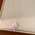 Dettaglio di un ciondolo a fiore in zircone e fiocco in smalto viola su una catena sottile. - Argento-Viola
