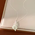 Primo piano del ciondolo con fiori in zircone e fiocco in smalto verde chiaro - Argento-Bianco