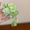 Detailed view of a handmade green fabric flower hair clip with pearl tassels - Light Green Peony Style
