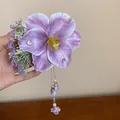 Detailed view of a handmade purple fabric flower hair clip with pearl tassels. - Purple Rhinestone Tassel Style