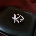 Close-up of a silver starfish open ring with sparkling zirconia on a black box. - Open (HR3311) / Silver