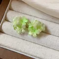 Close-up of elegant green resin flower stud earrings on a beige jewelry display tray - Style 3 (HE31330)