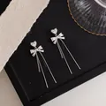 Detail of silver bowknot earrings featuring zircon heart studs and long tassels. - Bowknot Long Tassel (HE32055) / Silver