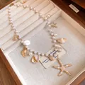 Detailed macro shot of pearl necklace featuring golden starfish and sea shell charms - Gold-White