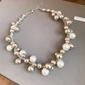 Gros plan d'un collier de perles vintage et de perles argentées sur fond gris texturé. - Collier ras-du-cou / Argent, Blanc