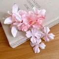 Detailopname van roze stoffen bloem haarclip met kwastjes op een boekachtergrond - Eendenbek haarclips / Roze