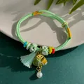 Close-up of handmade green woven bracelet featuring a triangular charm and pearl - Multi-color Rope Bracelet / Gold-Green