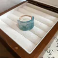 Macro view of light blue resin ring with 'Fu' engraving and elegant woven band - Ring / Blue