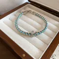 Detailed view of braided blue thread and silver link bracelet with CZ ring charm in a box - Bracelet / Blue