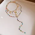 Close-up of bohemian multilayer necklace with pearls, seashells and colorful rhinestones. - Gold