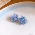 Dettaglio macro della lavorazione con perline cangianti viola e blu degli orecchini uva - Ago d'argento / Lavanda