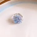Primo piano di un delicato anello a grappolo con perle iridescenti viola e blu - Anello / Lavanda