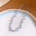 Dettaglio ravvicinato di una collana di perle a forma di uva su un piatto bianco - Collana / Lavanda