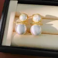Detailed shot of elegant brushed gold and silver stud earrings with pearls in a box - Silver