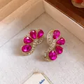 Exquisite close-up detail of vintage fuchsia gemstone earrings with gold floral setting - Rose Red
