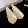 Primo piano di orecchini dorati a goccia sfaccettati con finitura metallica - Gualcito/Martellato / Ago d'argento / Oro