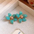 Macro detail of vintage floral stud earrings featuring turquoise beads and gems - Gold-Blue-Purple