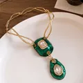 Macro detail of retro emerald green pendants with sparkling crystal accents on gold chain. - Necklace (HN11818) / Gold Green