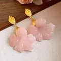 Detailed view of elegant pink resin flower earrings with gold-tone leaf posts - Gold-Pink
