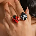 Primo piano di anelli a coccinella rossi e neri con motivi a cuore sulla mano di una modella - Contrasto Multicolore