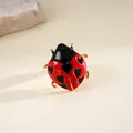 Primo piano di anello coccinella in smalto rosso con cuori e finitura in metallo dorato. - Oro-Rosso