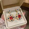 Gros plan de boucles d'oreilles style cour vintage avec pierres rouges et bleues - Or-Rouge-Bleu