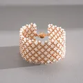 Detailed view of the geometric glass beadwork and spherical magnetic clasp of the bracelet. - Bracelet / Gold-White